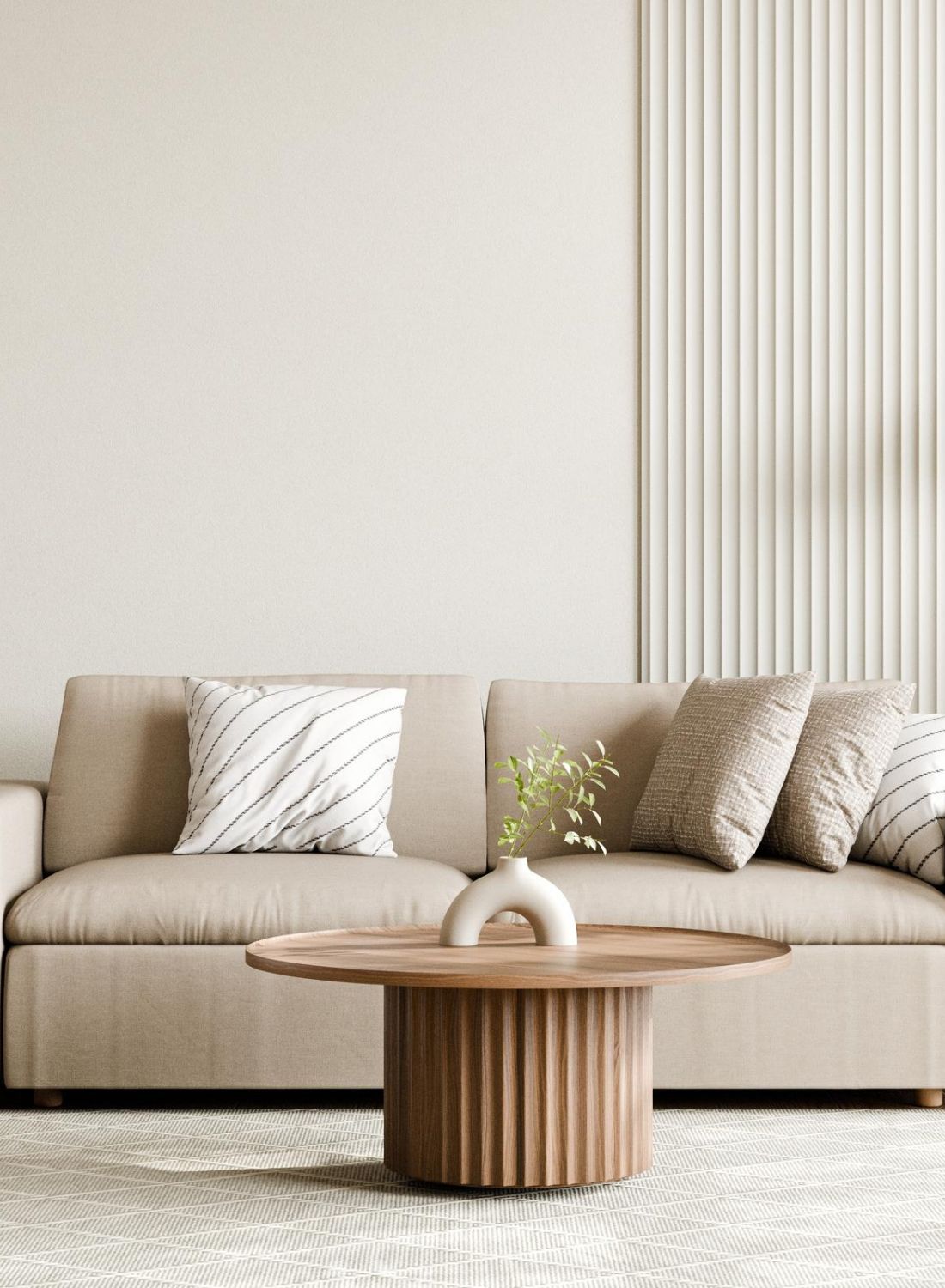 Modern living room with beige sofa, round wooden coffee table, floor lamp, side table, and plants.