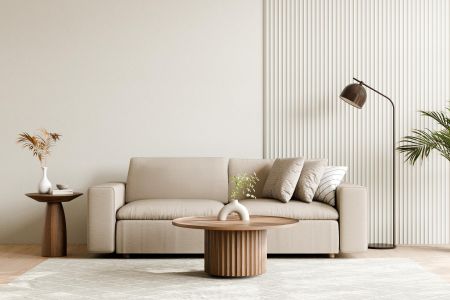 Minimalist living room with beige sofa, round coffee table, floor lamp, and neutral decor accents.